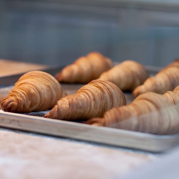 Golden-brown croissants on a baking sheet, ready to be served at Bistro La Baguette.