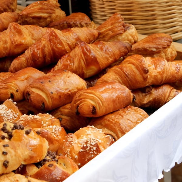 A close-up of a variety of golden-brown French pastries, including croissants and pain au chocolat.