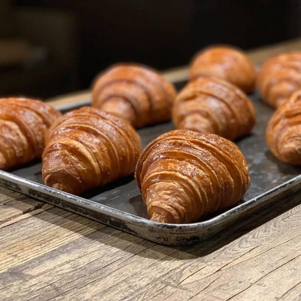 Golden-brown, flaky croissants fresh from the oven, arranged on a dark baking sheet at Bistro La Baguette.